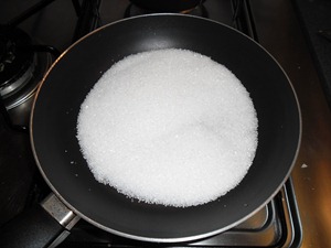 Doe een kop gewone suiker in een kleine koekenpan en verhit dit op redelijk hoog vuur terwijl u roert